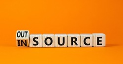 Outsource or insource symbol. Turned a wooden cube and changed the concept word Outsource to Insource. Beautiful orange table orange background, copy space. Business outsource or insource concept.