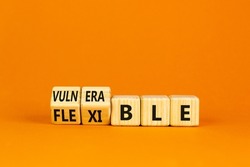 Vulnerable or flexible symbol. Turned wooden cubes and changed words 'vulnerable' to 'flexible'. Beautiful orange background, copy space. Business, vulnerable or flexible concept.