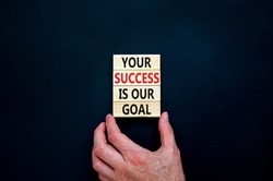 Your success is our goal symbol. Concept words Your success is our goal on wooden blocks. Businessman hand. Beautiful black table, black background, copy space. Success business goal concept.