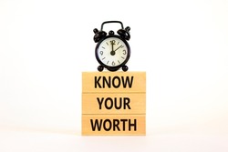 Know your worth symbol. Concept words Know your worth on wooden blocks. Black alarm clock. Beautiful white table white background. Business and know your worth concept. Copy space.