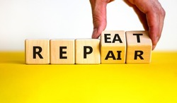 Repeat and repair symbol. Businessman turns wooden cubes and changes the word 'repeat' to 'repair'. Beautiful yellow table, white background, copy space. Business, repeat and repair concept.