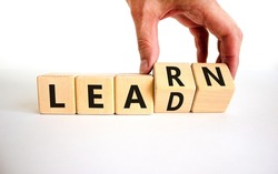 Learn and lead symbol. Businessman turns wooden cubes, changes the word 'learn' to 'lead'. Beautiful white table, white background. Business, educational, learn and lead concept. Copy space.