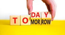 Do it today not tomorrow. Businessman turns wooden cubes and changes the word 'tomorrow' to 'today'. Beautiful yellow table, white background, copy space. Business and tomorrow or today concept.