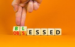 Blessed or obsessed symbol. Businessman turns wooden cubes and changes the concept word Obsessed to Blessed. Beautiful orange table orange background. Business blessed or obsessed concept. Copy space.