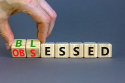 Blessed or obsessed symbol. Businessman turns wooden cubes and changes the concept word Obsessed to Blessed. Beautiful grey table grey background. Business blessed or obsessed concept. Copy space.