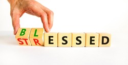 Blessed or stressed symbol. Businessman turns wooden cubes and changes the concept word Stressed to Blessed. Beautiful white table white background. Business blessed or stressed concept. Copy space.