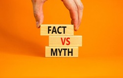Fact vs myth symbol. Concept words Fact vs myth on wooden blocks on a beautiful orange table orange background. Businessman hand. Business, finacial and fact vs myth concept. Copy space.