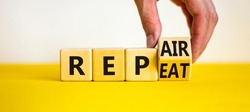 Repeat and repair symbol. Businessman turns a wooden cube and changes the word repeat to repair. Beautiful yellow table, white background, copy space. Business, repeat and repair concept.
