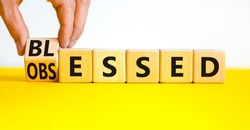 Blessed or obsessed symbol. Businessman turns wooden cubes and changes the concept word Obsessed to Blessed. Beautiful yellow table white background. Business blessed or obsessed concept. Copy space.