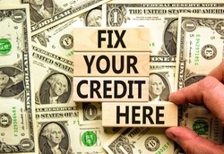 Fix your credit here symbol. Concept words Fix your credit here on wooden blocks on a beautiful background from dollar bills. Businessman hand. Business, finacial and fix your credit here concept.