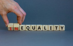 Equality or inequality symbol. Businessman turns woden cubes, changes the word inequality to equality. Beautiful grey background. Psychology, business and equality or inequality concept. Copy space.