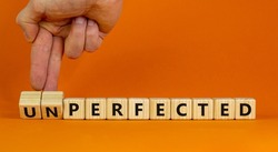 Perfected or unperfected symbol. Businessman turns wooden cubes and changes the word unperfected to perfected on a beautiful orange background. Business, perfected or unperfected concept. Copy space.