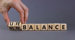Work life balance symbol. Businessman turns cubes and changes concept words Work balance to Life balance. Beautiful grey table grey background. Business work life balance concept. Copy space.
