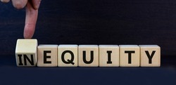 Inequity or equity symbol. Turned wooden cubes and changed the concept word Inequity to Equity. Beautiful grey table grey background. Business and inequity or equity concept. Copy space.