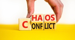 From conflict to chaos symbol. Concept words Conflict and Chaos on wooden cubes. Businessman hand. Beautiful yellow table white background. Business Conflict and Chaos concept. Copy space.