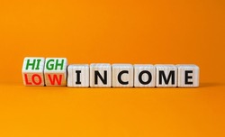 Low or high income symbol. Turned wooden cubes and changed concept words Low income to High income. Beautiful orange table orange background, copy space. Business low or high income concept.