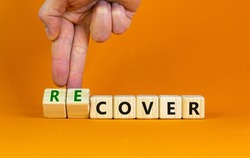 Time to recover symbol. Businessman turns wooden cubes and changes the word 'cover' to 'recover'. Beautiful orange table, orange background. Business, cover or recover concept. Copy space.