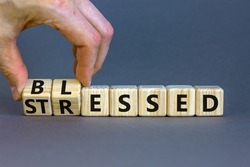 Blessed or stressed symbol. Businessman turns wooden cubes and changes the concept word Stressed to Blessed. Beautiful grey table grey background. Business blessed or stressed concept. Copy space.
