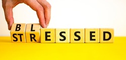 Blessed or stressed symbol. Businessman turns wooden cubes and changes the concept word Stressed to Blessed. Beautiful yellow table white background. Business blessed or stressed concept. Copy space.