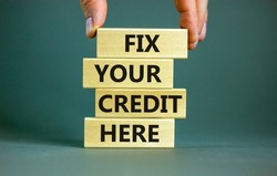 Fix your credit here symbol. Concept words Fix your credit here on wooden blocks on a beautiful grey table grey background. Businessman hand. Business, finacial and fix your credit here concept.