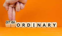 Ordinary or extraordinary symbol. Businessman turnes wooden cubes and changes words 'Ordinary extraordinary'. Beautiful orange background. Business, Copy space.