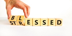Blessed or stressed symbol. Businessman turns wooden cubes and changes the concept word Stressed to Blessed. Beautiful white table white background. Business blessed or stressed concept. Copy space.