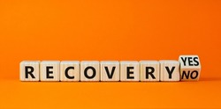 Recovery symbol. Turned a wooden cube and changed words 'recovery no' to 'recovery yes'. Beautiful orange background. Business and recovery concept, copy space.