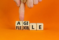 Flexible and agile symbol. Concept words Flexible and agile on wooden cubes. Businessman hand. Beautiful orange table orange background. Business flexible and agile concept. Copy space.
