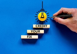 Fix your credit symbol. Concept words Fix your credit on wooden blocks on a beautiful blue table blue background. Businessman hand. Business, finacial and fix your credit concept. Copy space.