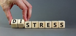 Stress or distress symbol. Psychologist turns cubes and changes the concept word Stress to Distress. Beautiful grey table grey background, copy space. Psychlogical distress or stress concept.