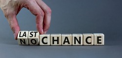 No or last chance symbol. Businessman turns wooden cubes and changes words 'no chance' to 'last chance'. Beautiful grey background, copy space. Business and no or last chance concept.
