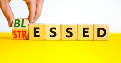 Blessed or stressed symbol. Businessman turns wooden cubes and changes the concept word Stressed to Blessed. Beautiful yellow table white background. Business blessed or stressed concept. Copy space.