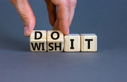 Wish and do it symbol. Businessman turns cubes and changes words 'wish it' to 'do it'. Beautiful grey table, grey background. Business and wish and do it concept. Copy space.