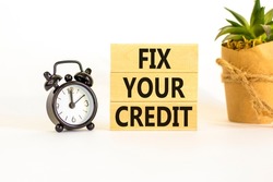 Fix your credit symbol. Concept words Fix your credit on wooden blocks on a beautiful white table white background. Black alarm clock. Business, finacial and fix your credit concept. Copy space.