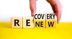 Recovery and renew symbol. Businessman turns cubes and changes the word 'recovery' to 'renew '. Beautiful yellow table, white background. Business and recovery - renew concept. Copy space.