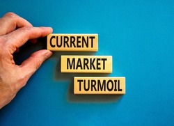 Current market turmoil symbol. Concept words Current market turmoil on wooden blocks on a beautiful blue table blue background. Businessman hand. Business, finacial current market turmoil concept.