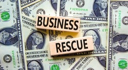 Business rescue symbol. Concept words Business rescue on wooden blocks on a beautiful background from dollar bills. Business rescue and support concept. Copy space.