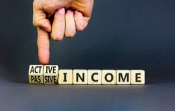 Passive or active income symbol. Businessman turns wooden cubes and changes words passive income to active income. Beautiful grey background, copy space. Business, passive or active income concept.