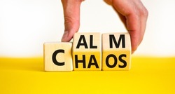 Stop chaos, time to calm. The concept words Chaos and Calm on wooden cubes. Beautiful yellow table white background, copy space. Businessman hand. Business and chaos or calm concept.