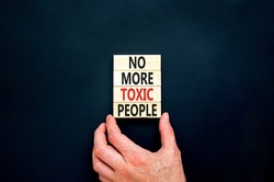 No more toxic people symbol. Concept words No more toxic people on wooden blocks on a beautiful black table black background. Psychologist hand. Business, psychological no more toxic people concept.