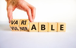 Vulnerable or variable symbol. Businessman turns wooden cubes and changes the word Vulnerable to Variable. Beautiful white background, copy space. Business and vulnerable or variable concept.