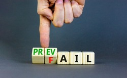 Prevail or fail symbol. Concept words Prevail or Fail on wooden cubes. Businessman hand. Beautiful grey table grey background. Business prevail or fail concept. Copy space.