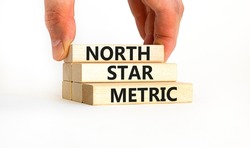 North star metric symbol. Concept words North star metric on wooden blocks on a beautiful white table white background. Businessman hand. Business finacial and north star metric concept. Copy space.