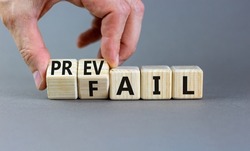 Prevail or fail symbol. Concept words Prevail or Fail on wooden cubes. Businessman hand. Beautiful grey table grey background. Business prevail or fail concept. Copy space.