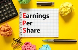 EPS earnings per share symbol. Concept words EPS earnings per share on white note on a beautiful yellow background. Black calculator. Business and EPS earnings per share concept. Copy space.