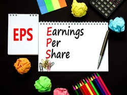 EPS earnings per share symbol. Concept words EPS earnings per share on white note on a beautiful black background. Businessman hand. Business and EPS earnings per share concept. Copy space.