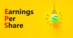 EPS earnings per share symbol. Concept words EPS earnings per share on a beautiful yellow background. Green light bulb icon. Business and EPS earnings per share concept. Copy space.