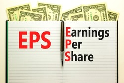 EPS earnings per share symbol. Concept words EPS earnings per share on white note on a beautiful white background. Dollar bills. Business and EPS earnings per share concept. Copy space.