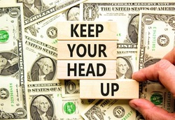 Keep your head up symbol. Concept words Keep your head up on wooden cubes. Beautiful background from dollar bills. Businessman hand. Business motivational keep your head up concept. Copy space.