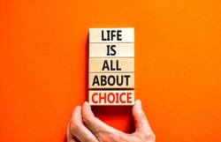 Choice and life symbol. Concept words Life is all about choice on wooden blocks. Beautiful orange table orange background. Businessman hand. Business choice and life concept. Copy space.